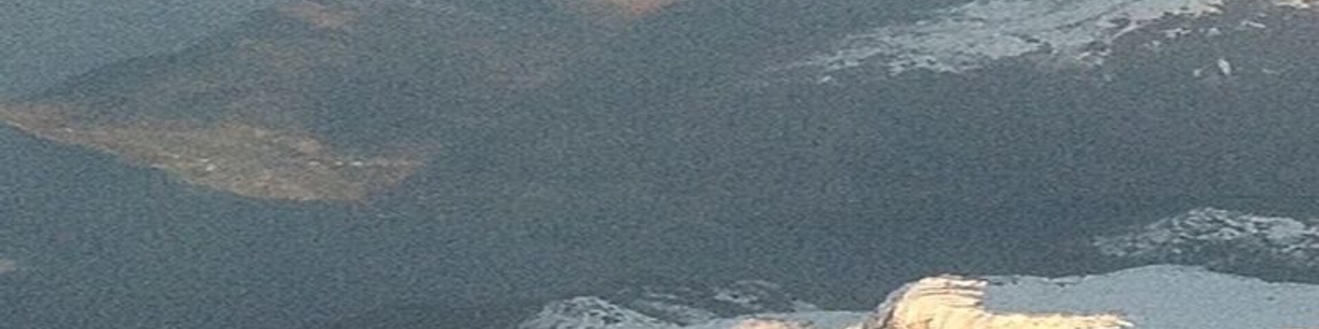 A snow-covered mountain range with rugged terrain and a valley.
