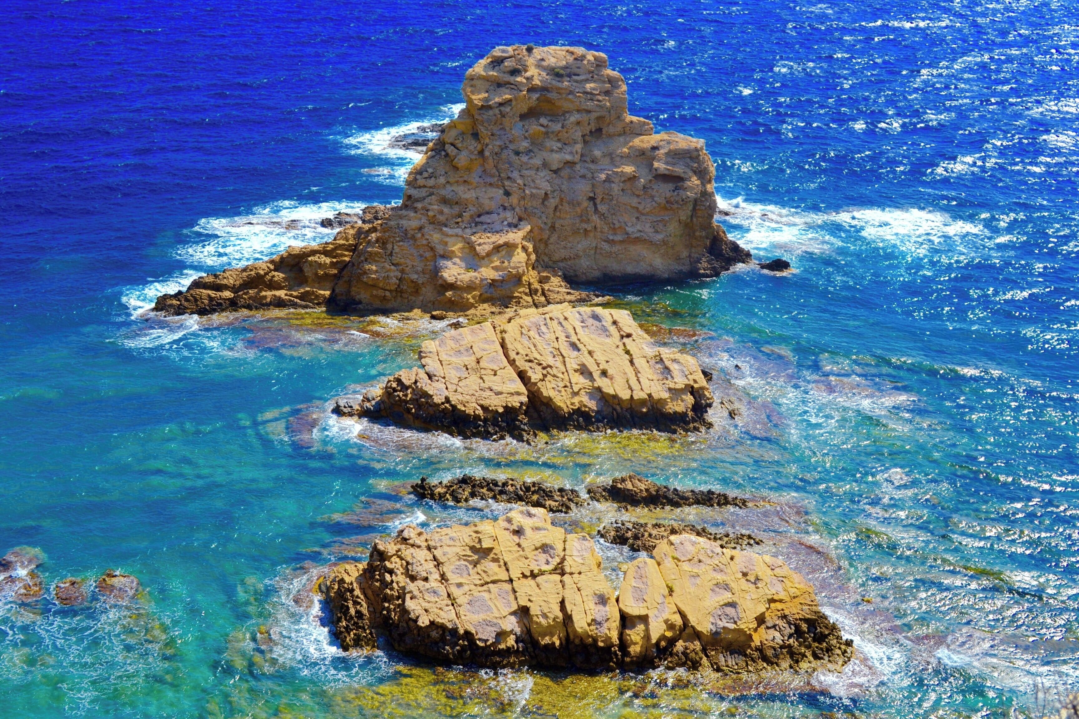 A rocky coastline with clear blue waters and a prominent rock formation.