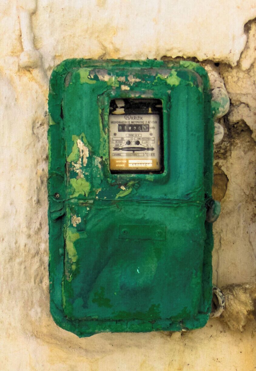 A green electrical box with a label, partially covered by peeling paint.