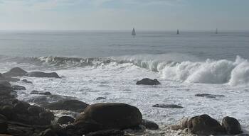 Atlantic Ocean seascape with crashing waves and sailboats near Canidelo, Vila Nova de Gaia, Porto, Portugal, January 2024
