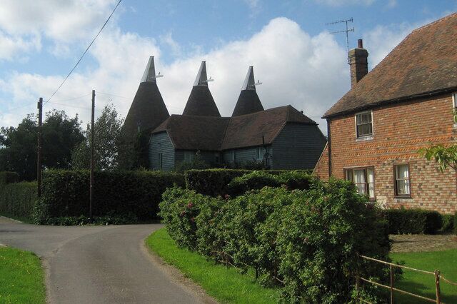 A rural road with a brick house and a building with conical roofs.