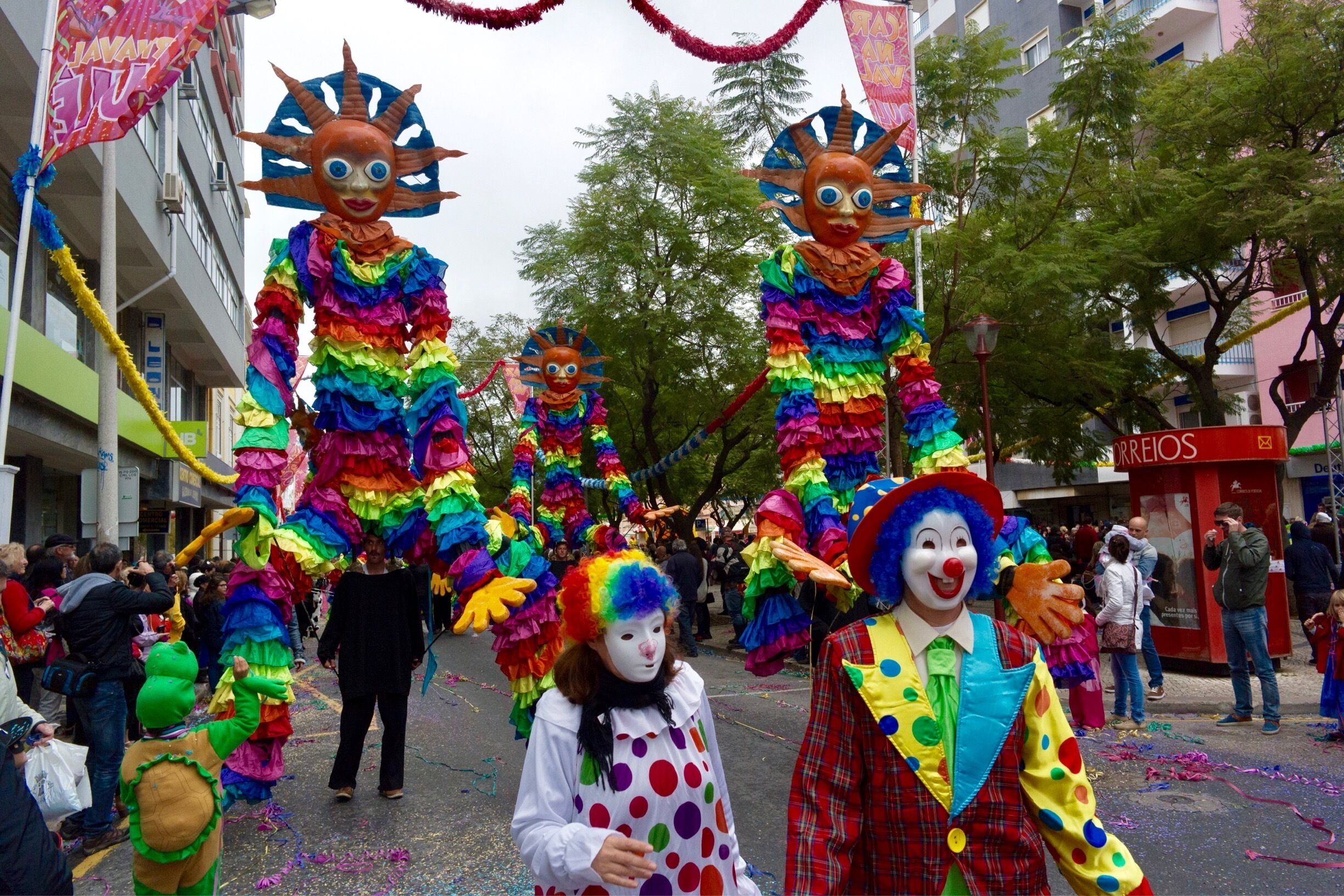 A street parade with colorful costumes and large masks.