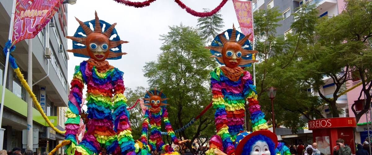 A street parade with colorful costumes and large masks.