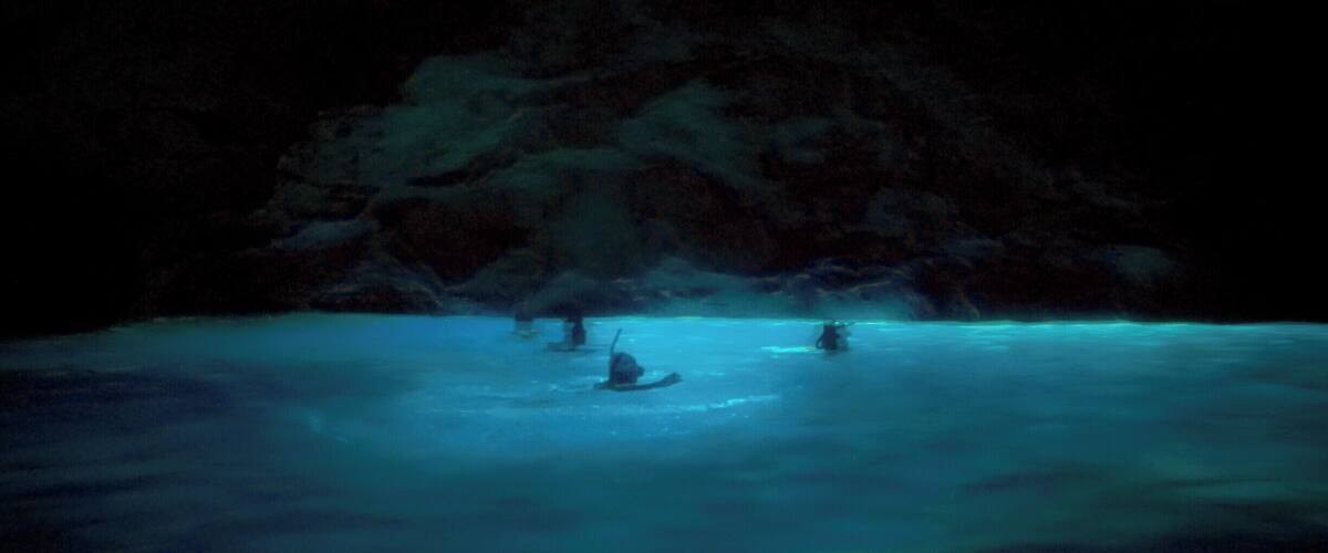 A cave entrance with water reflecting light.