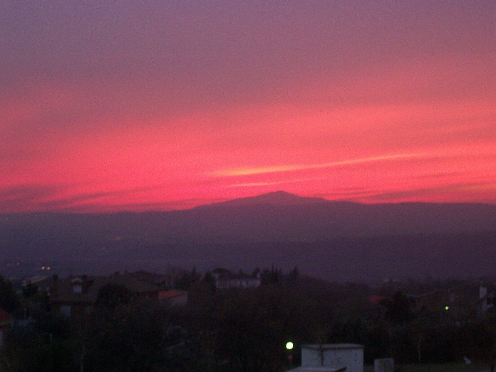 A sunset over a mountain range with a cityscape in the foreground.