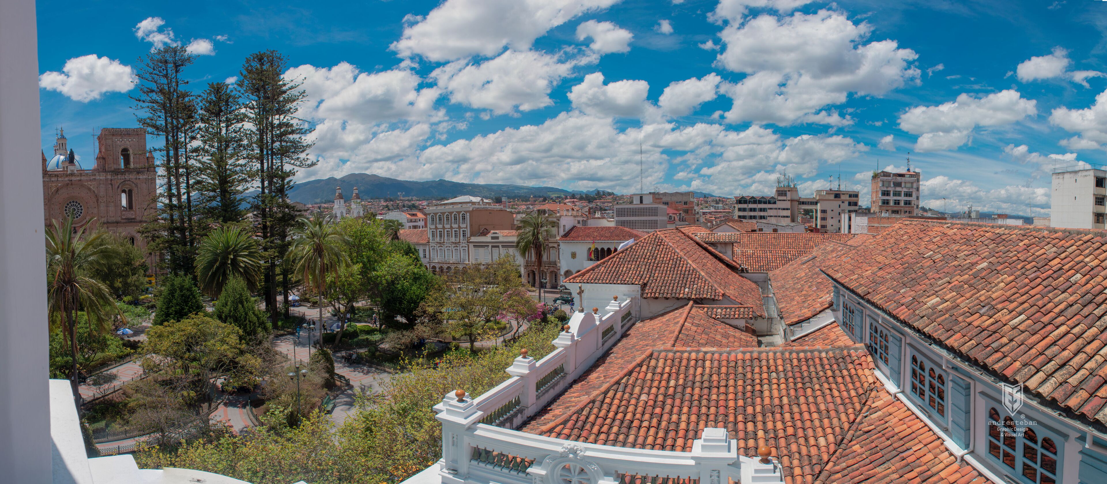 A cityscape with red-tiled roofs, a church with a dome, and a mountainous background.