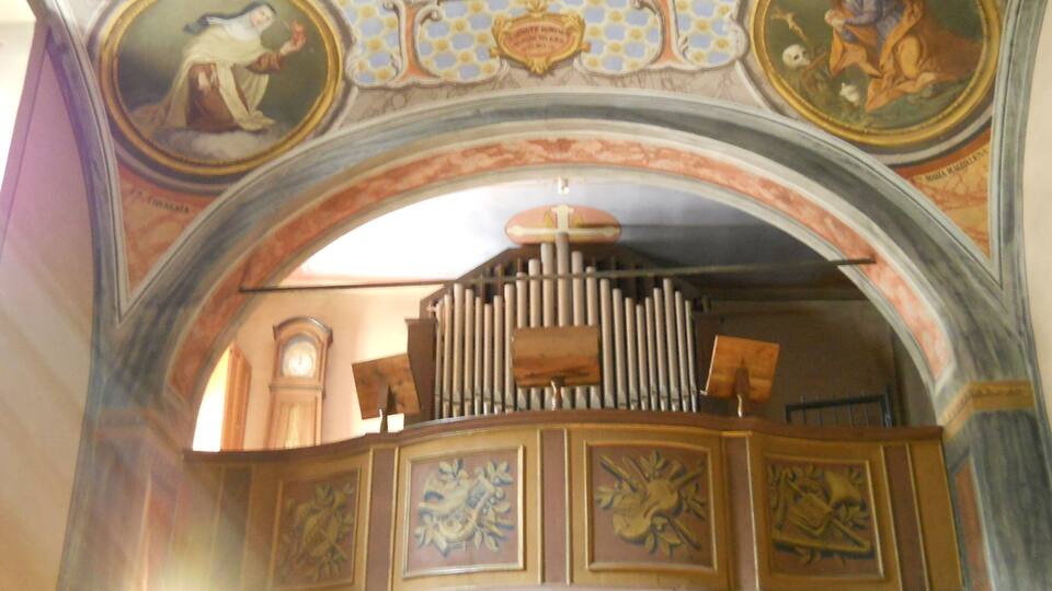 An ornate church interior with a large organ, detailed frescoes, and a clock.