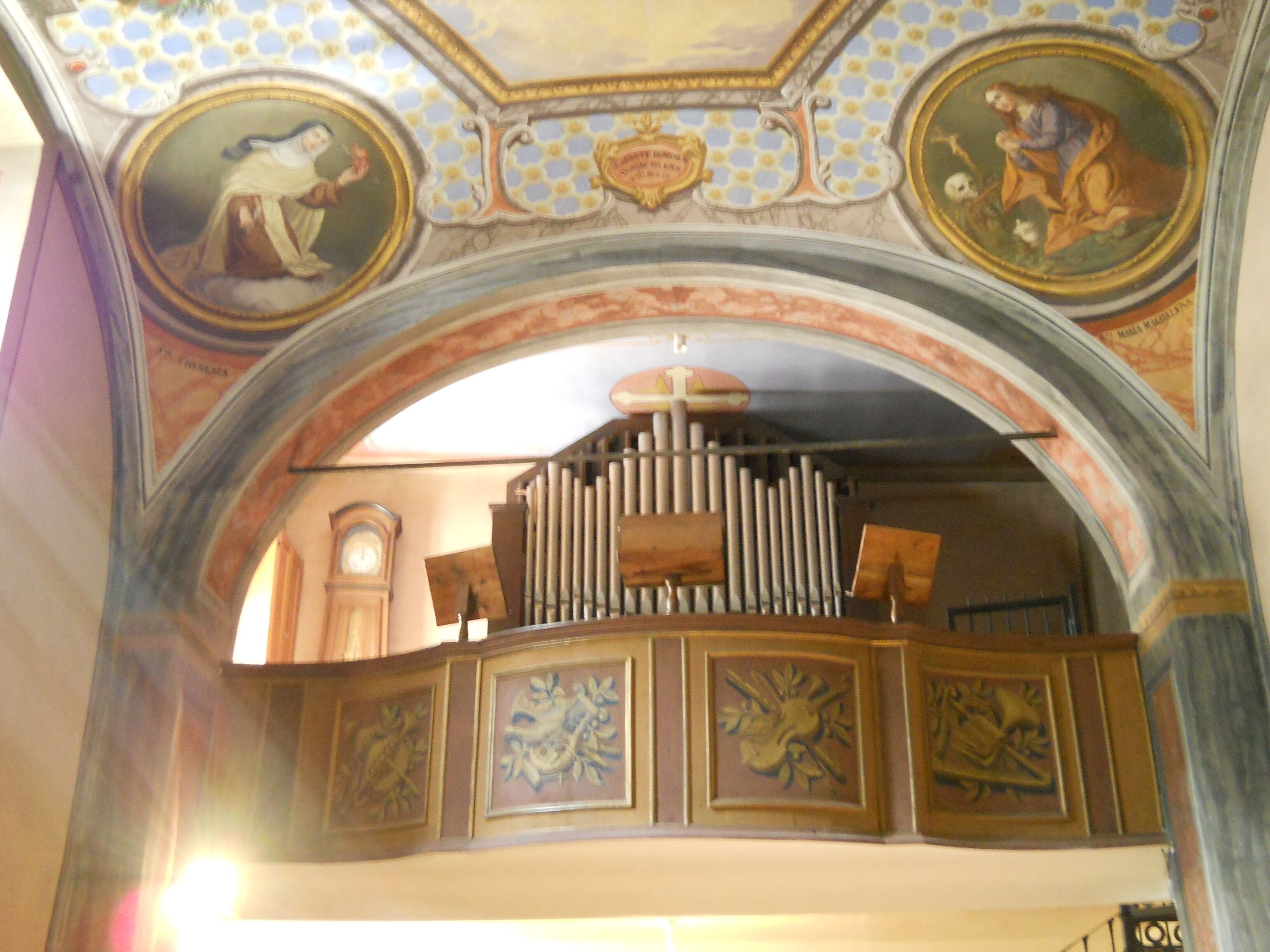 An ornate church interior with a large organ, detailed frescoes, and a clock.
