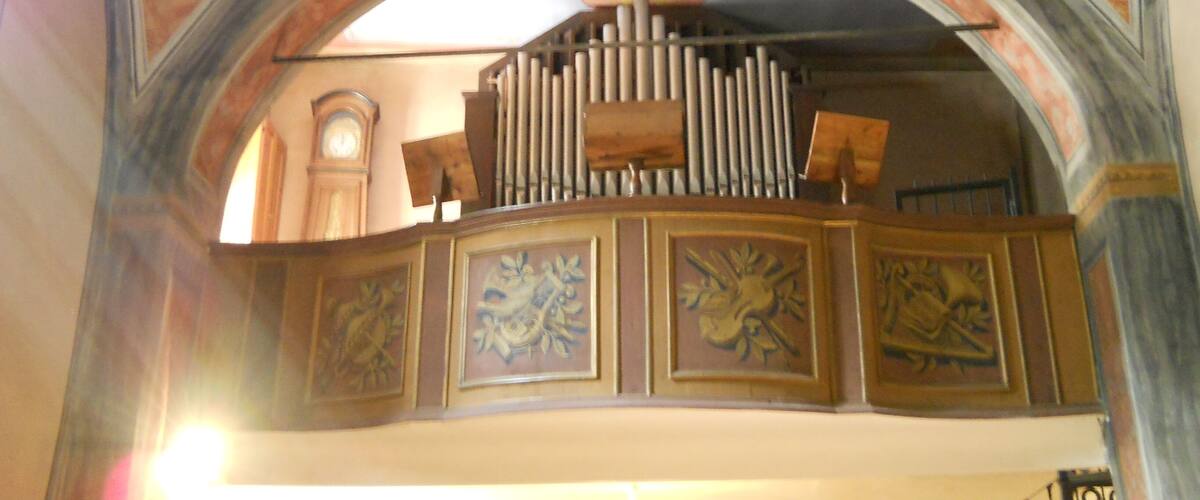 An ornate church interior with a large organ, detailed frescoes, and a clock.