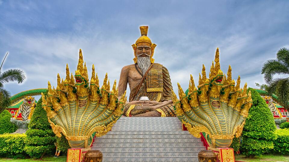 A large golden statue of a seated figure with elaborate headdresses, surrounded by ornate golden structures.