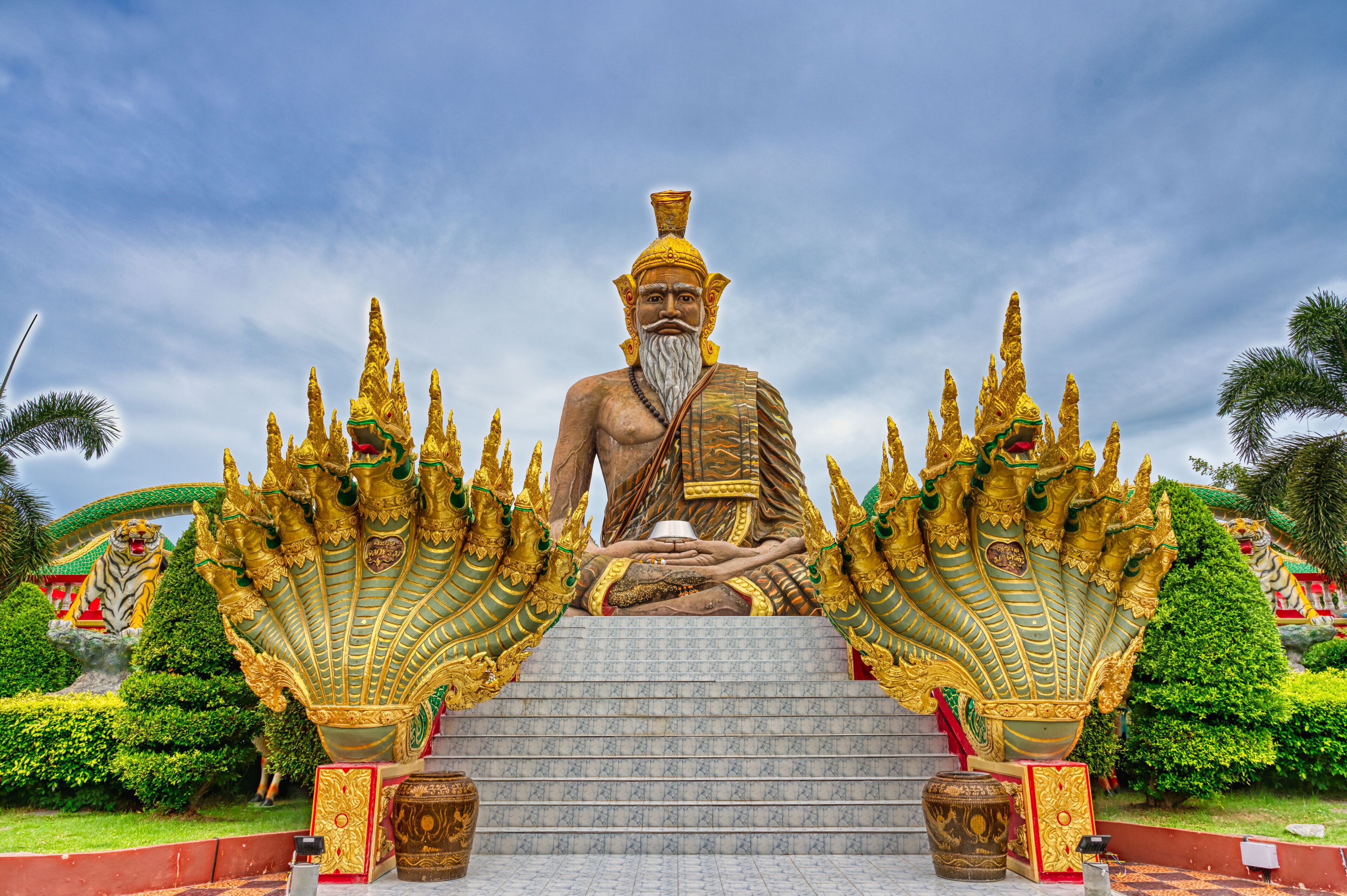 A large golden statue of a seated figure with elaborate headdresses, surrounded by ornate golden structures.