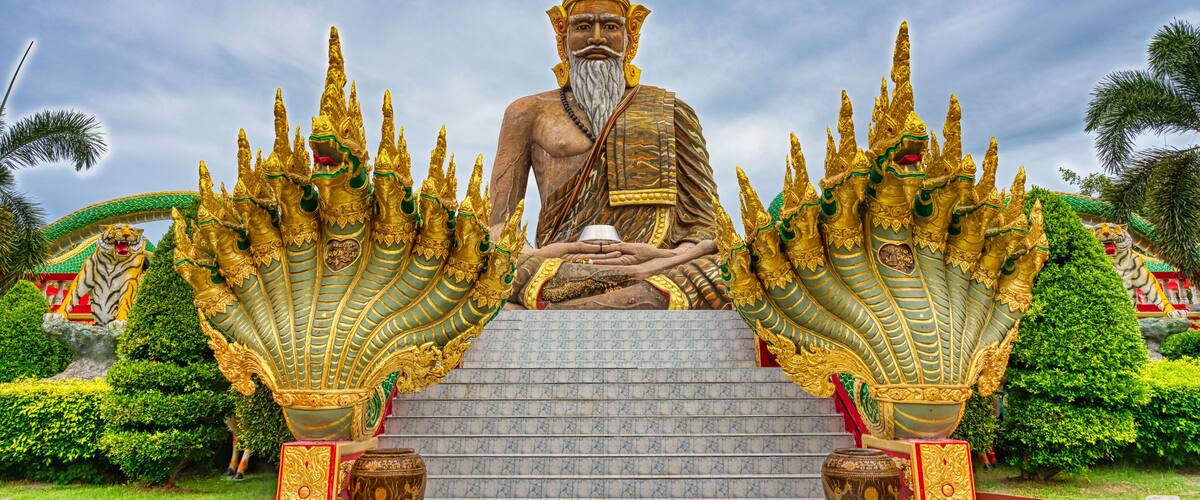 A large golden statue of a seated figure with elaborate headdresses, surrounded by ornate golden structures.