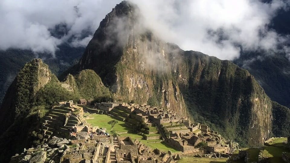 Machu Picchu, an ancient Incan city with terraced fields and stone structures, set against a backdrop of mist-covered mountains.