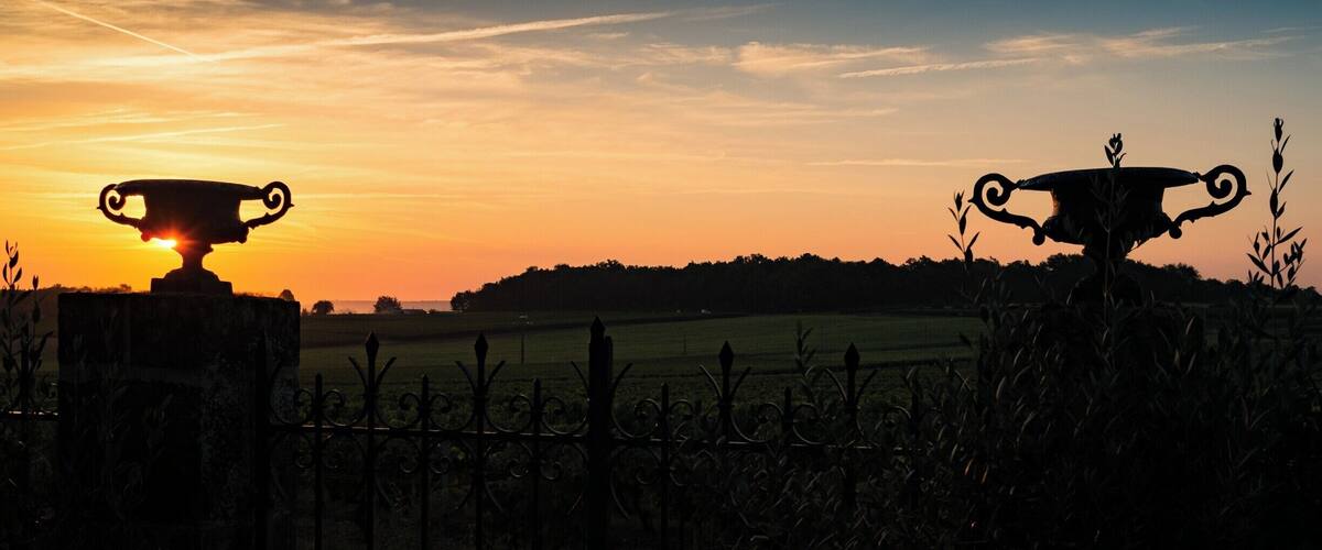 A sunset over a field with two trophies silhouetted against the sky.