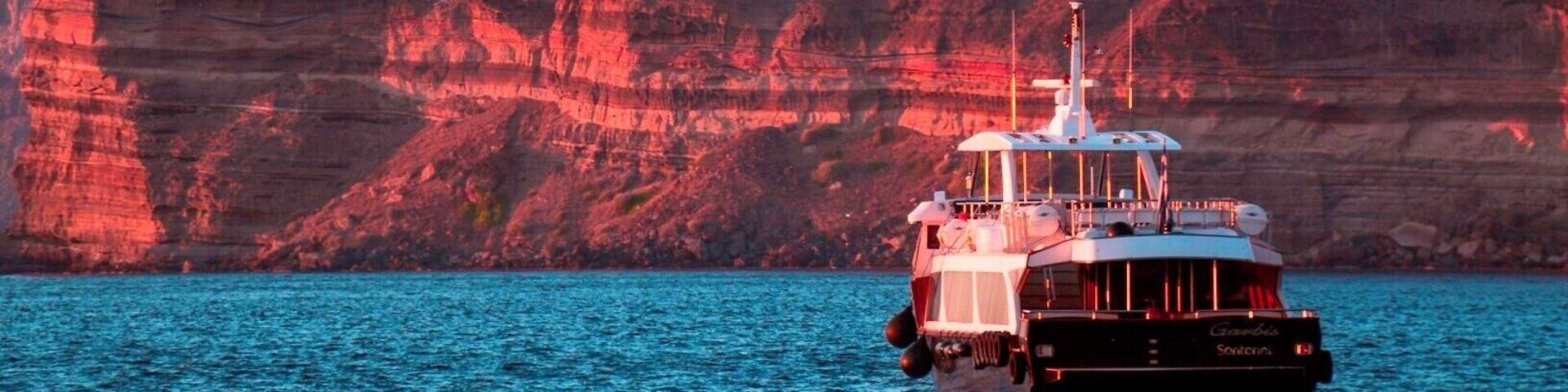A boat on a calm sea with red cliffs in the background.