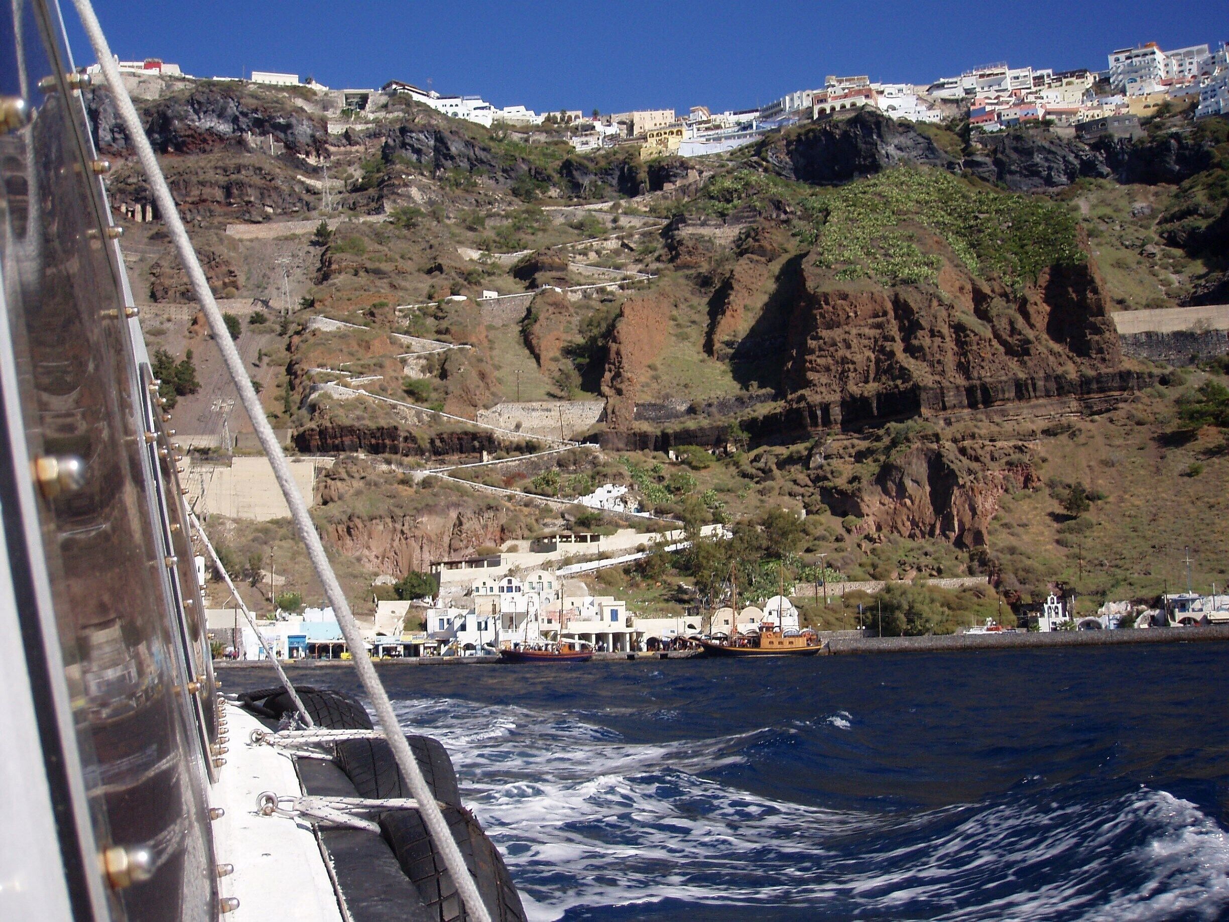 A coastal town with white buildings on a hillside, a rocky cliff, and the ocean.