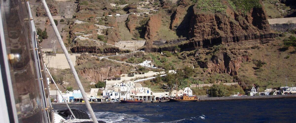 A coastal town with white buildings on a hillside, a rocky cliff, and the ocean.