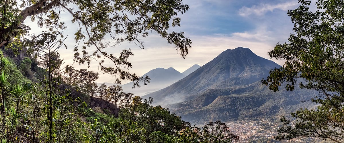 A mountain landscape with dense foliage and a town in the valley below.