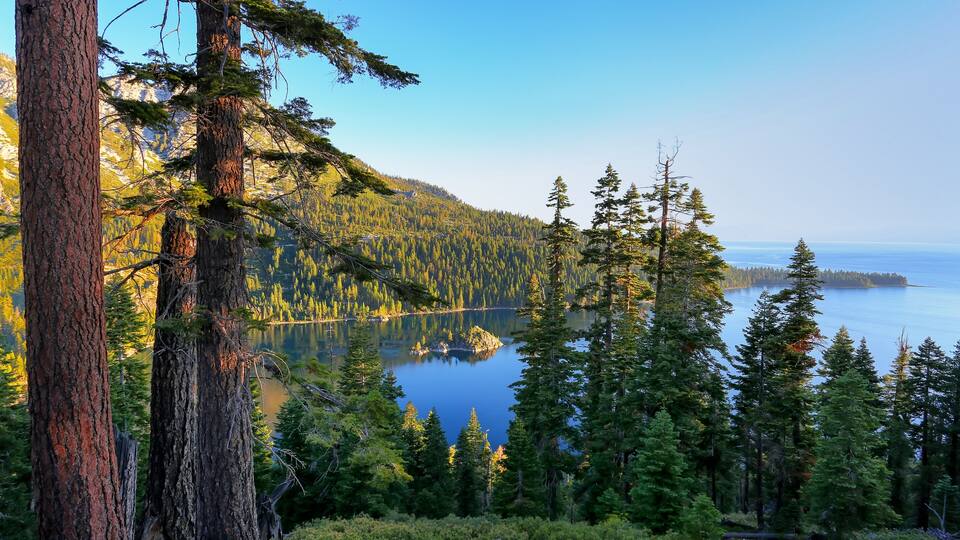 A forested mountain with a lake and a clear sky.