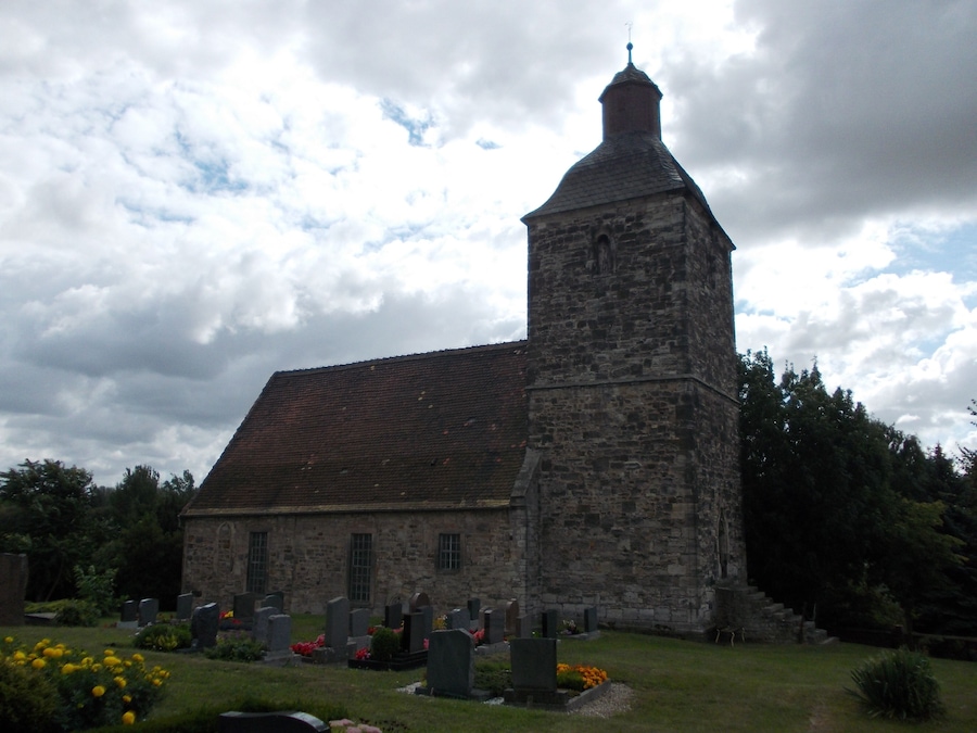 A church with a tall tower and a graveyard in front.