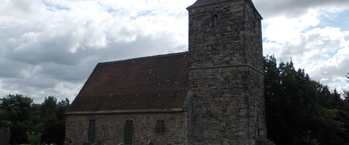 A church with a tall tower and a graveyard in front.