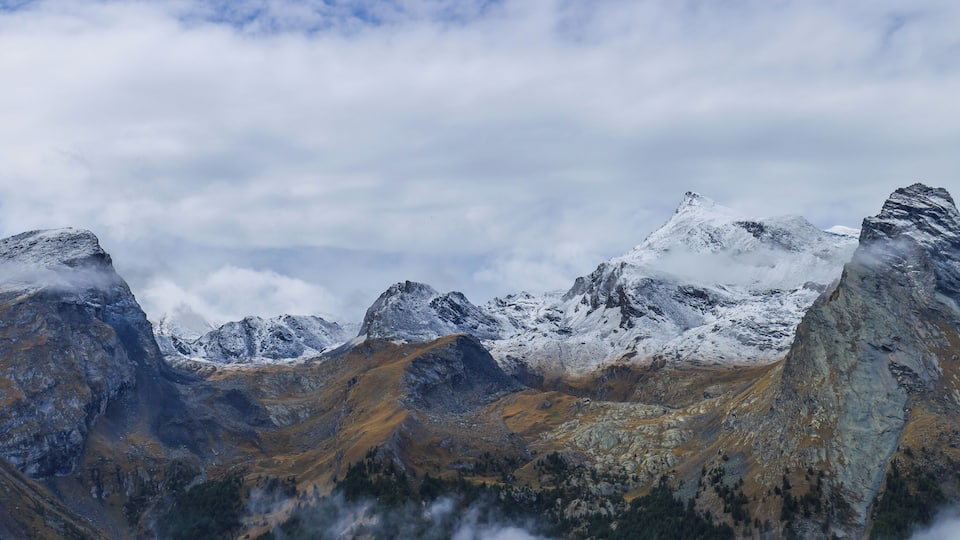 A mountain range with snow-capped peaks and rocky terrain.