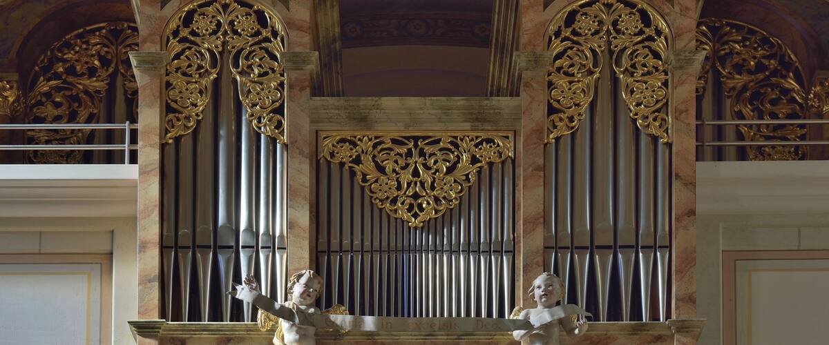 An ornate organ with golden decorations and two cherubs.