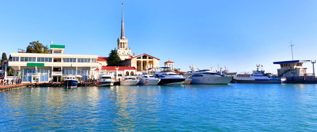A marina with several boats docked, a church with a tall spire, and a building with a green sign.