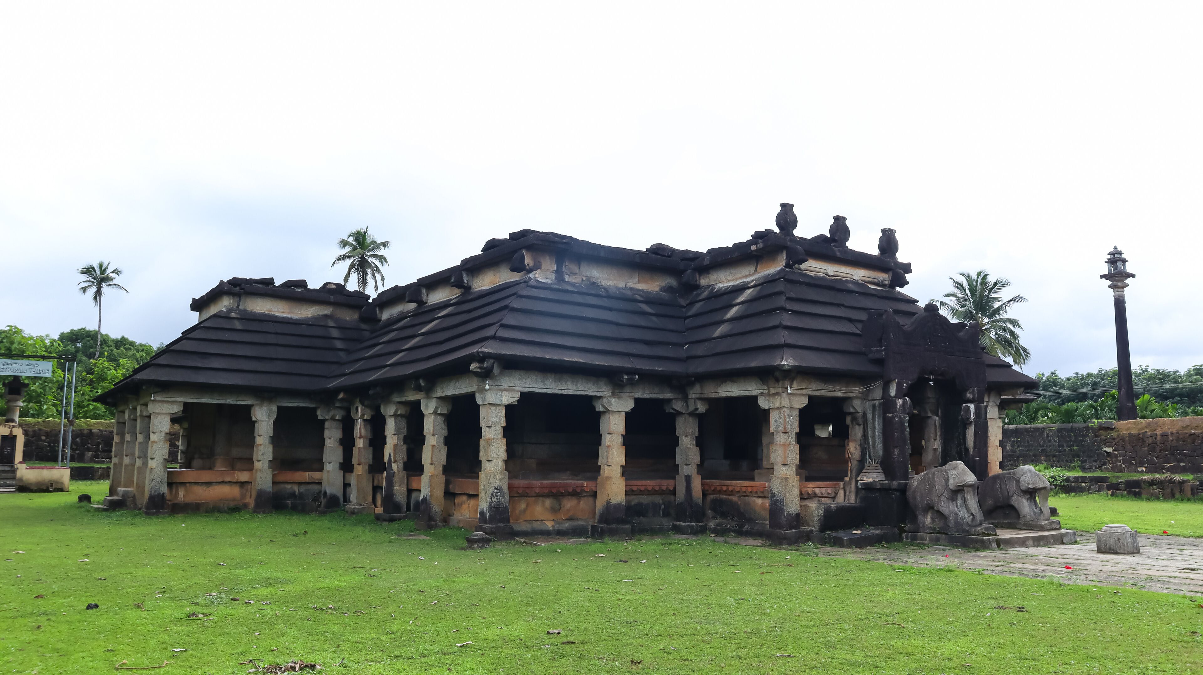 An ancient temple with stone pillars and a dark roof.