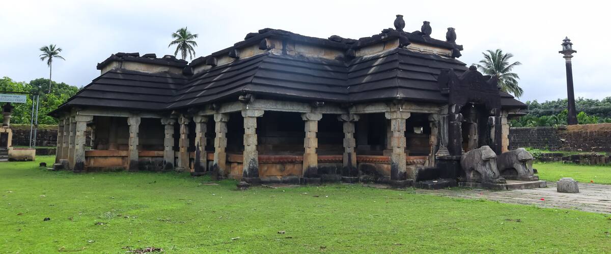 An ancient temple with stone pillars and a dark roof.