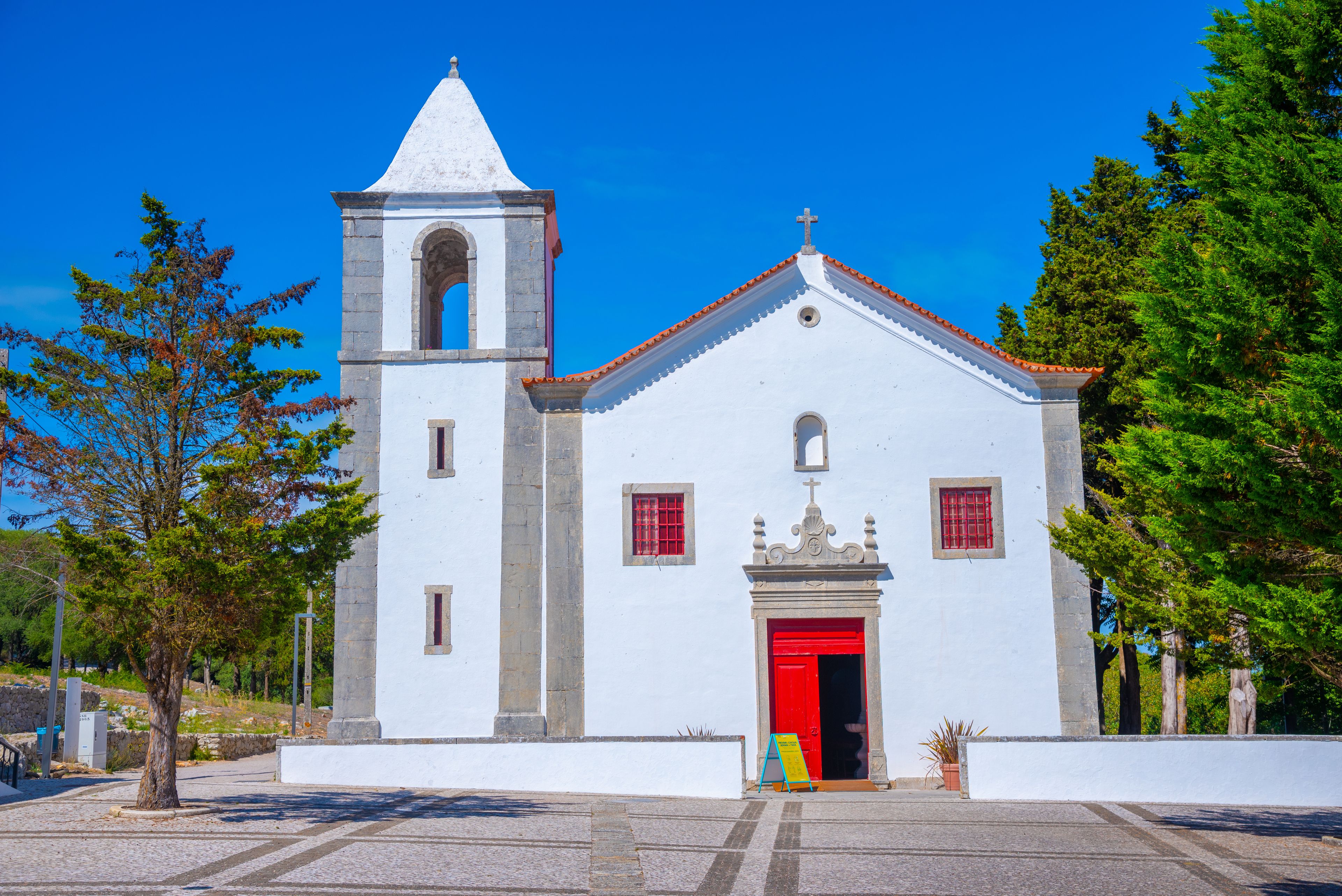 Una iglesia blanca con un campanario y una puerta roja.