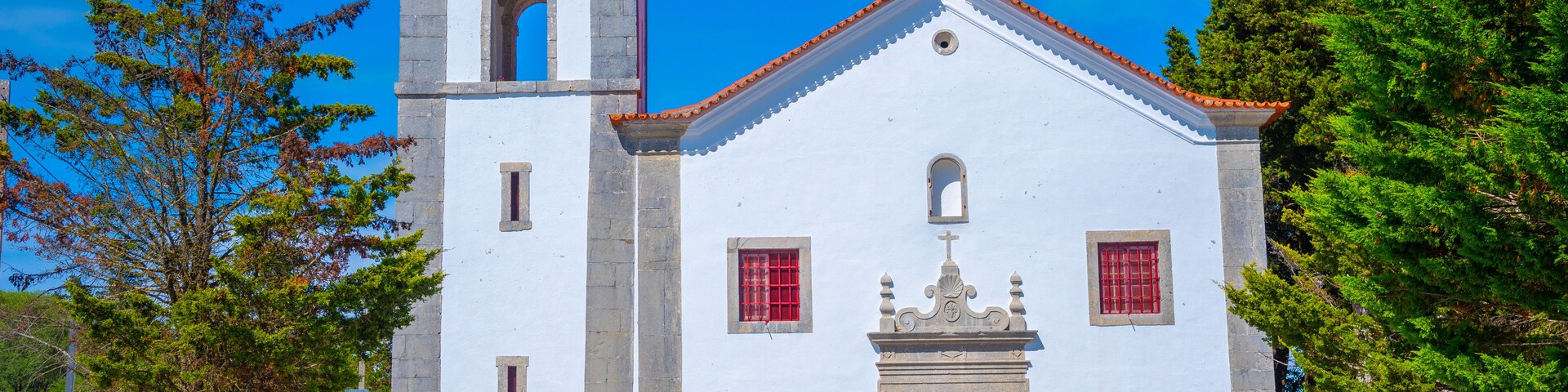 Una iglesia blanca con un campanario y una puerta roja.