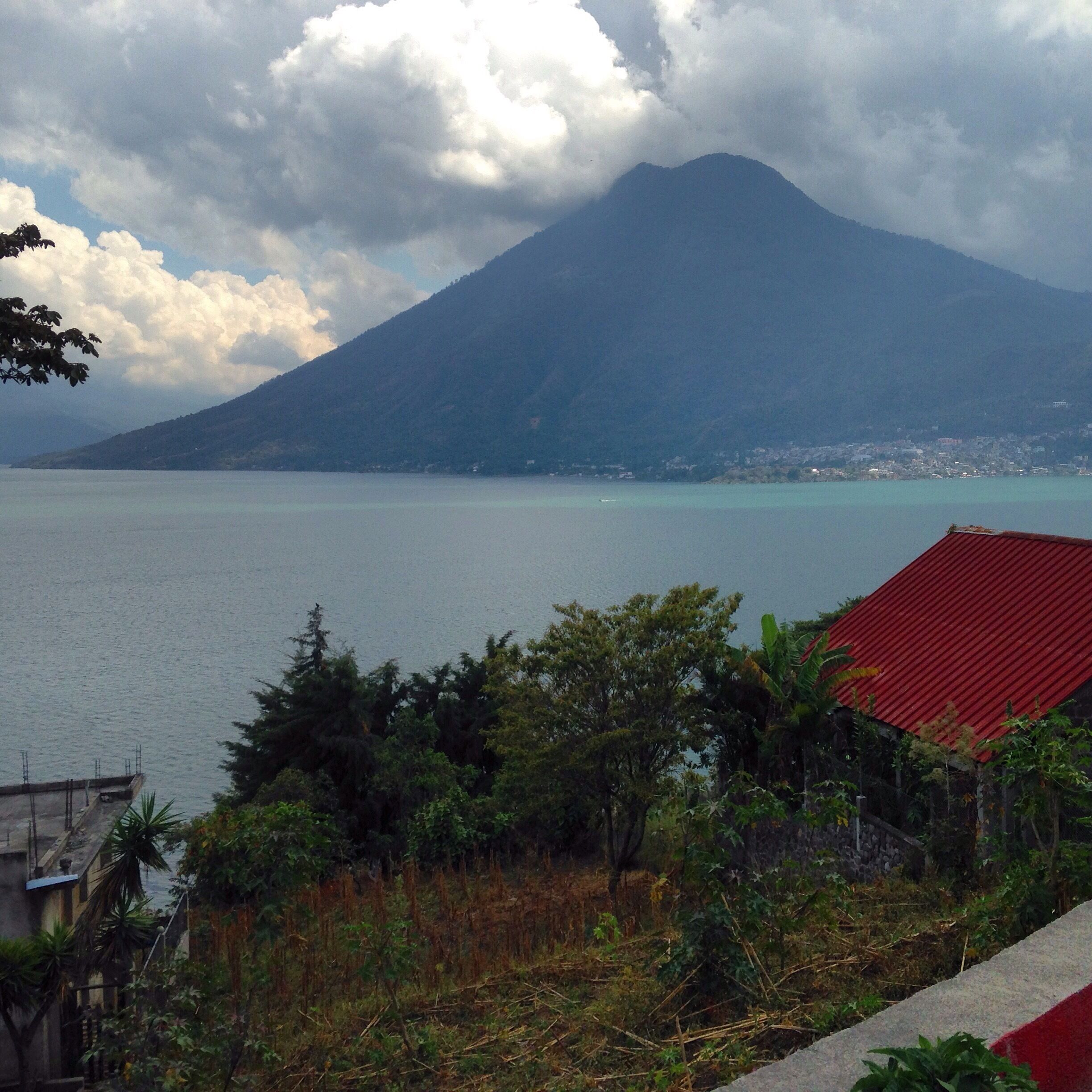 A mountain, a body of water, and a red-roofed building.