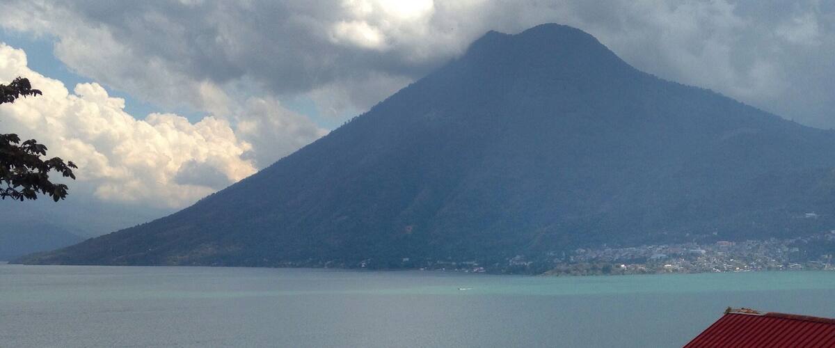 A mountain, a body of water, and a red-roofed building.