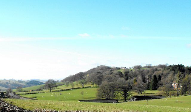 Rolling green hills, a few scattered trees, and a distant building.
