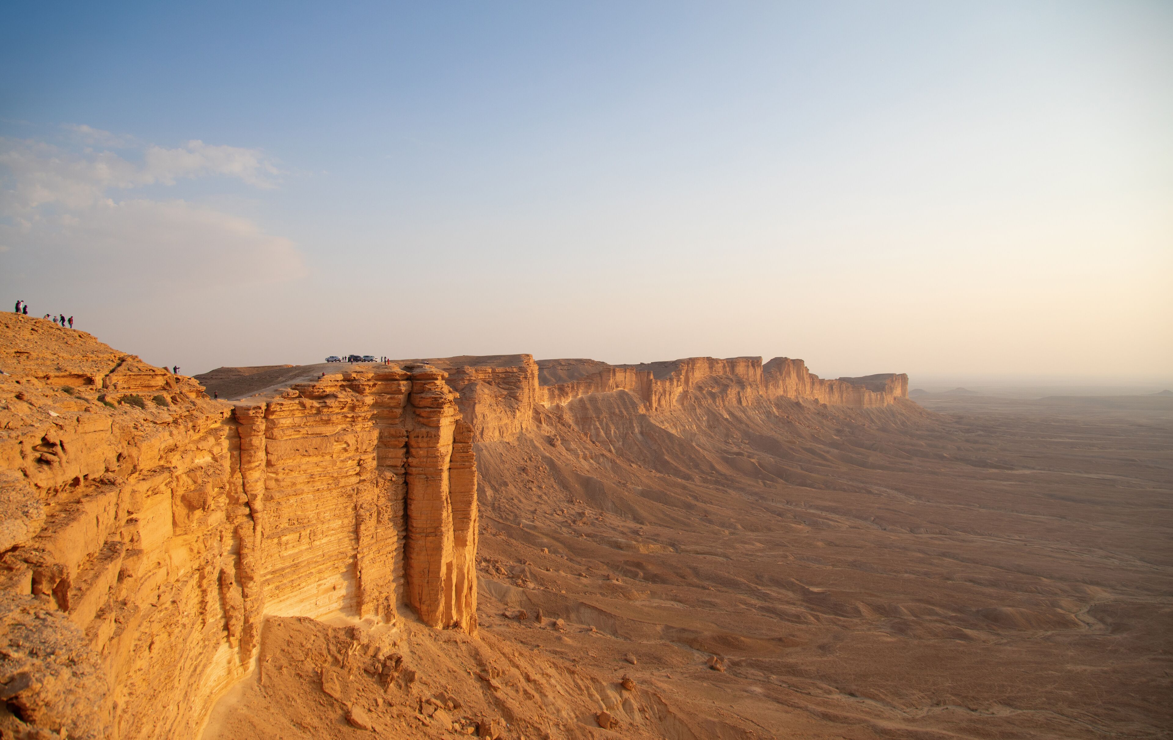 A desert landscape with layered rock formations and a clear sky.