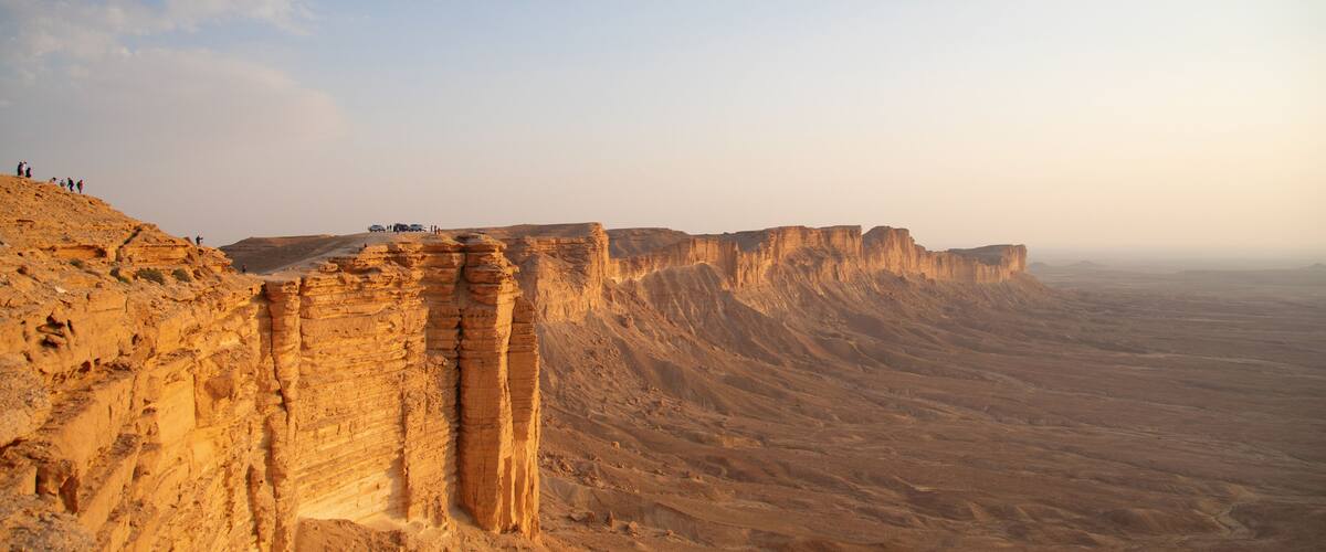 A desert landscape with layered rock formations and a clear sky.