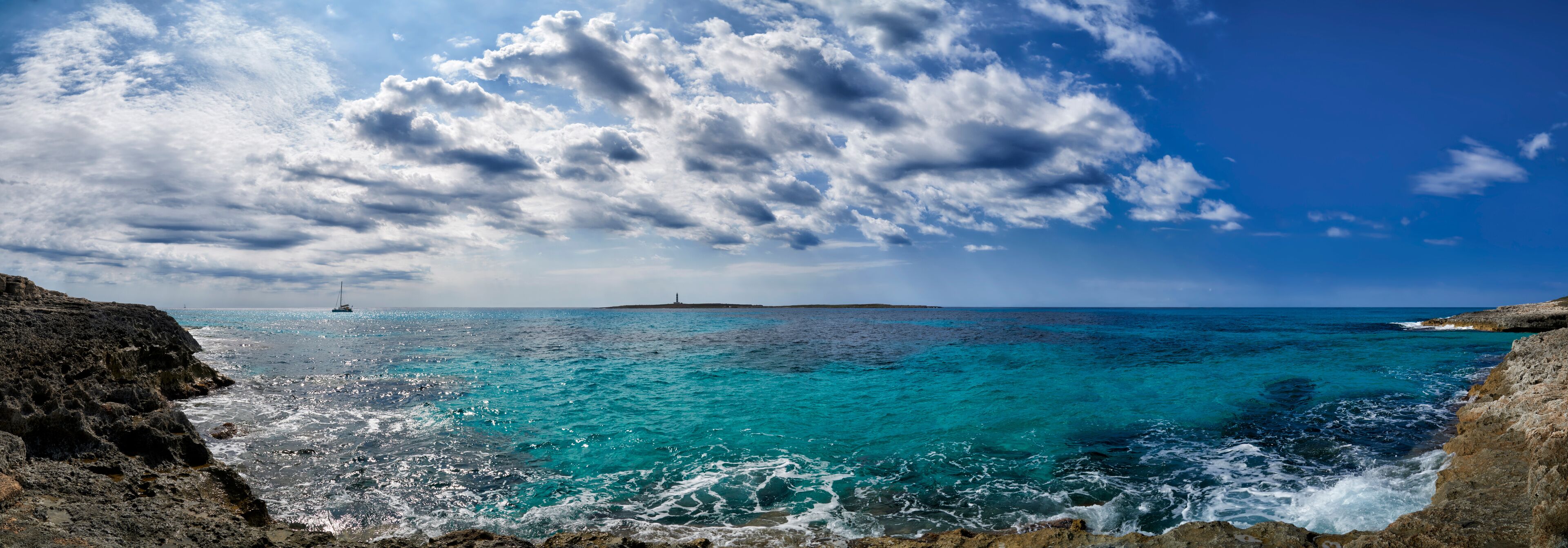 A coastal landscape with turquoise waters, rocky cliffs, and a lighthouse in the distance.