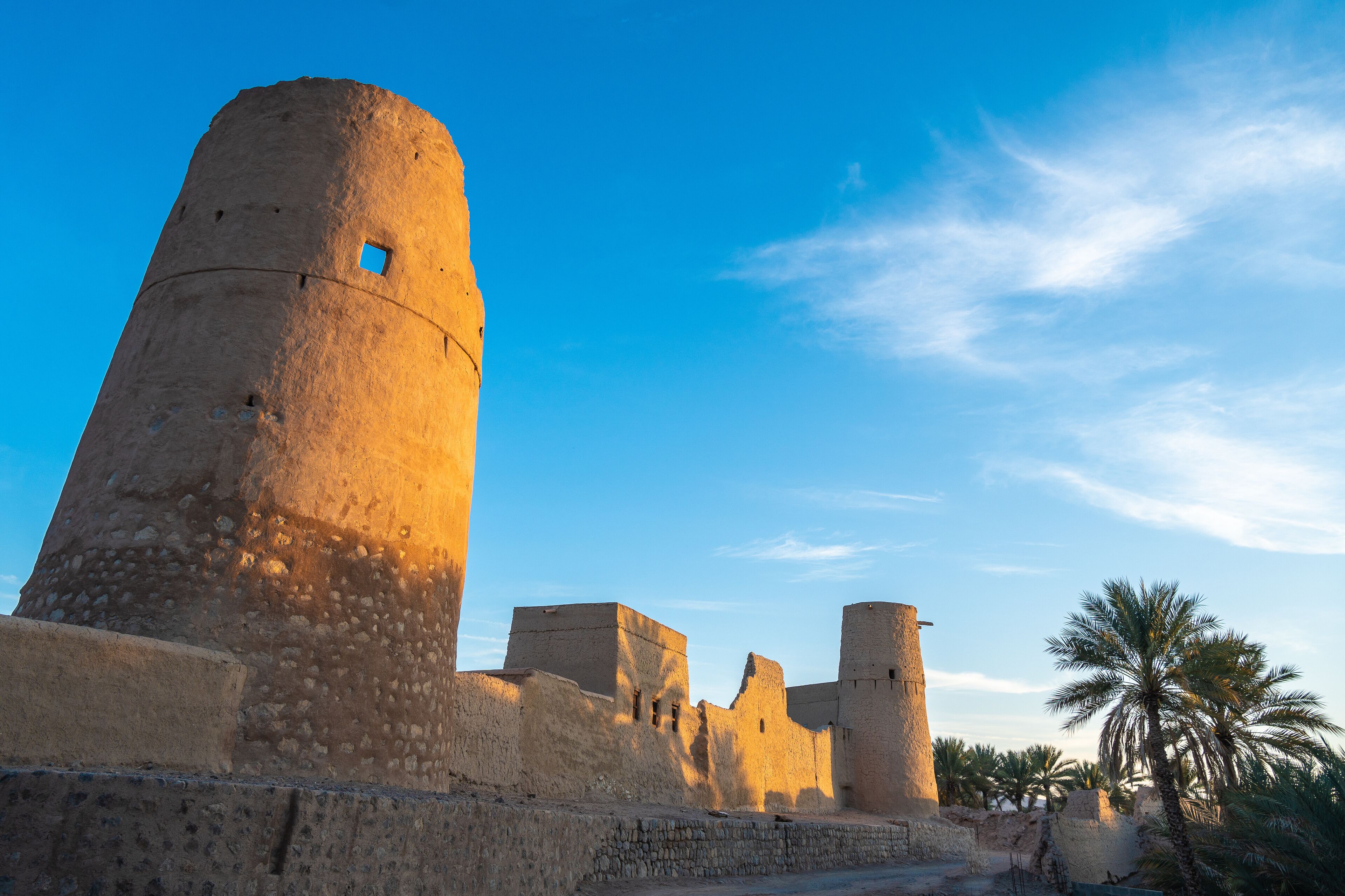 A historic fort with a prominent tower and palm trees in the foreground.