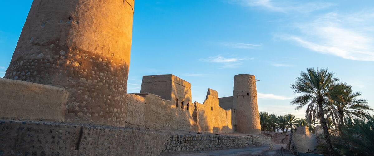 A historic fort with a prominent tower and palm trees in the foreground.