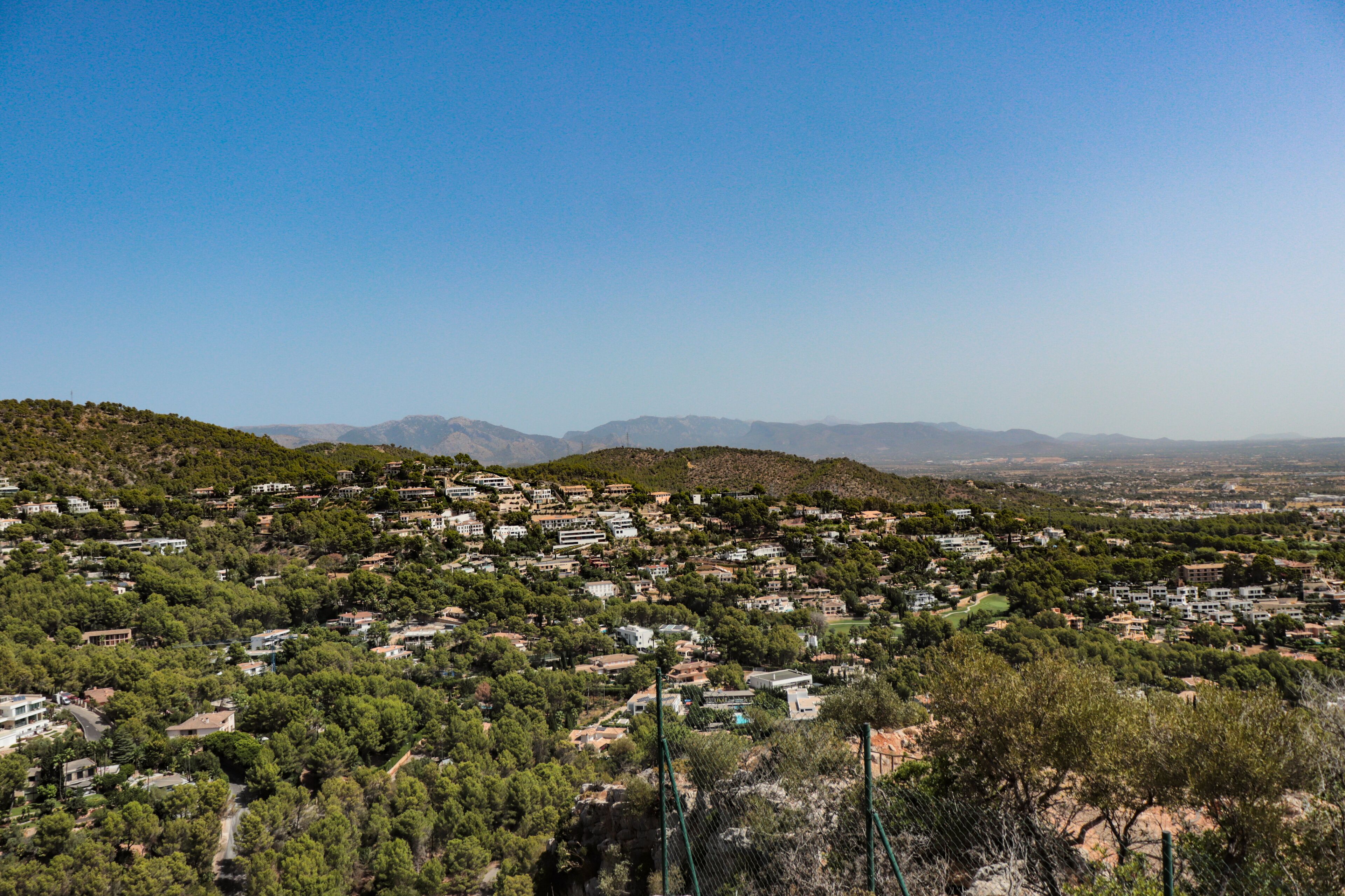 A residential area with houses and greenery on a hillside.