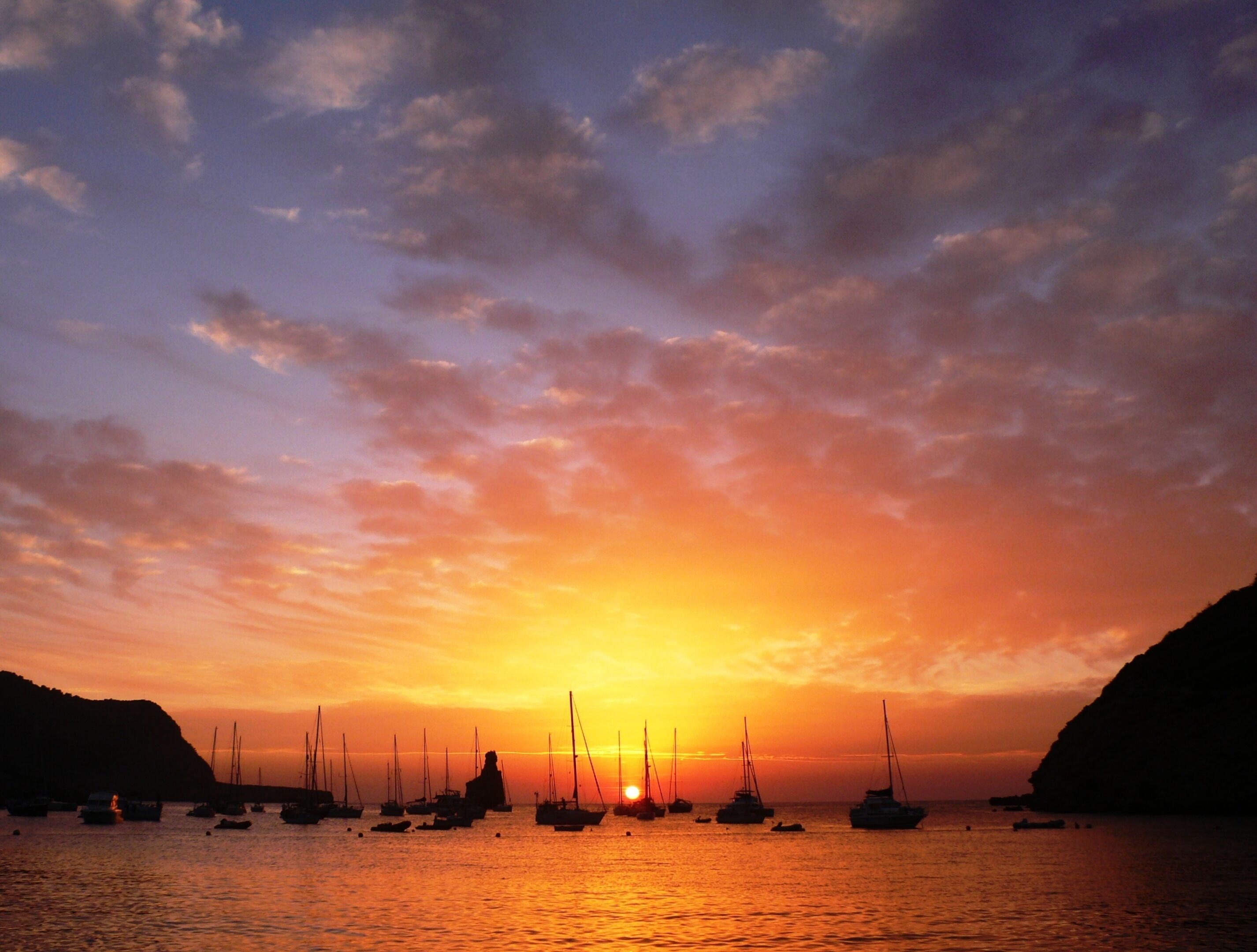 A sunset over a harbor with sailboats.
