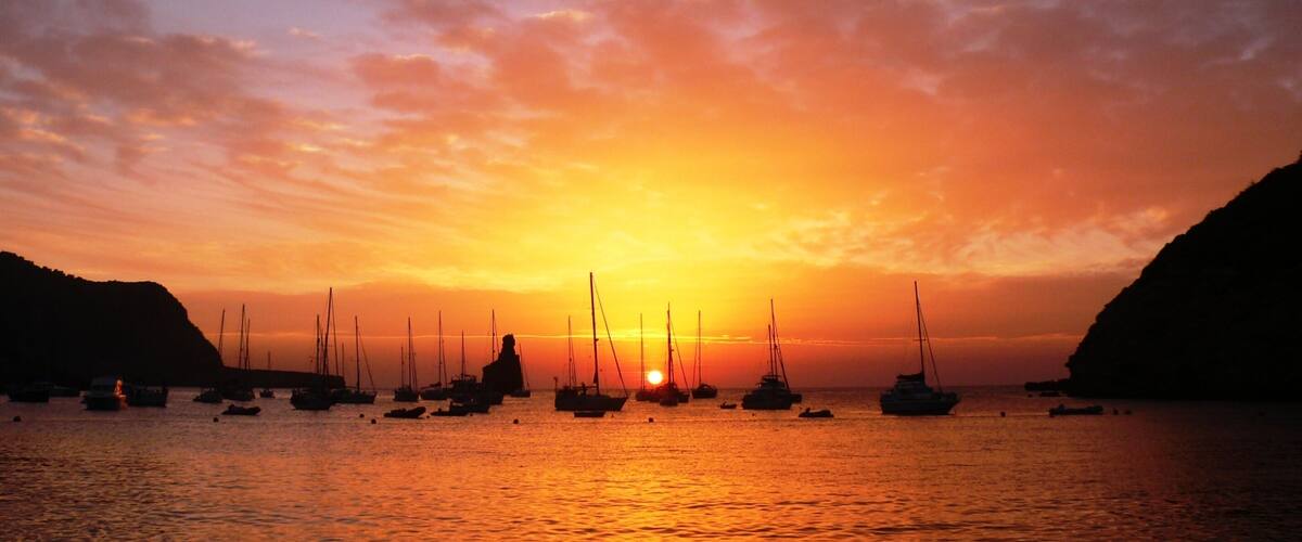 A sunset over a harbor with sailboats.