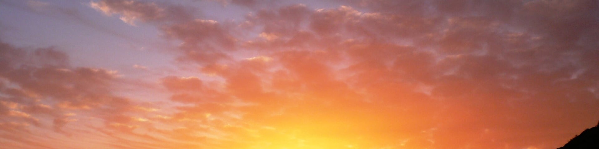 A sunset over a harbor with sailboats.
