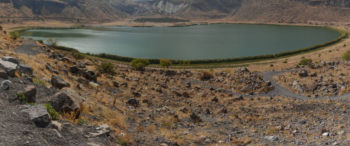 A large, circular lake surrounded by rocky hills and sparse vegetation.