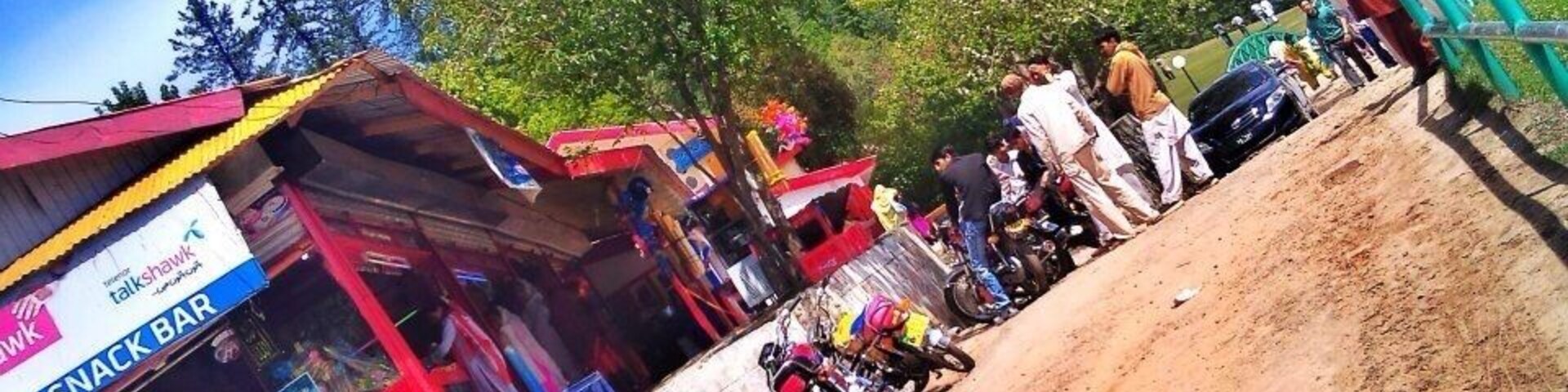 Un bar de aperitivos, un camino de tierra y un grupo de personas cerca de una montaña.