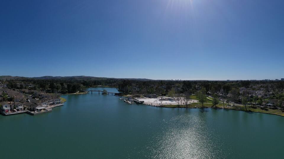 A river with houses on both sides, a bridge, and a clear blue sky.