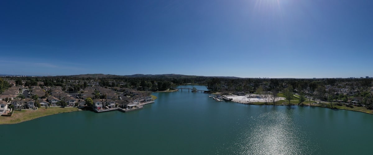 A river with houses on both sides, a bridge, and a clear blue sky.