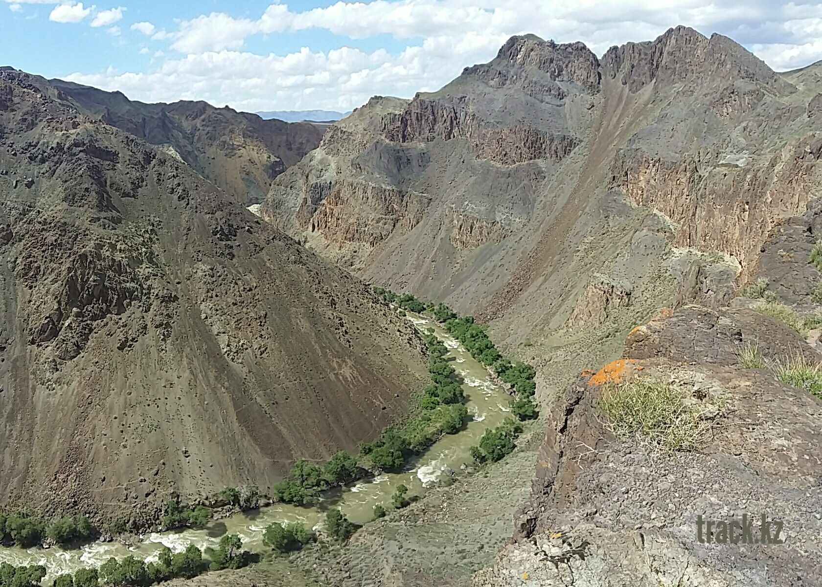 A rugged mountain landscape with a winding river and sparse vegetation.