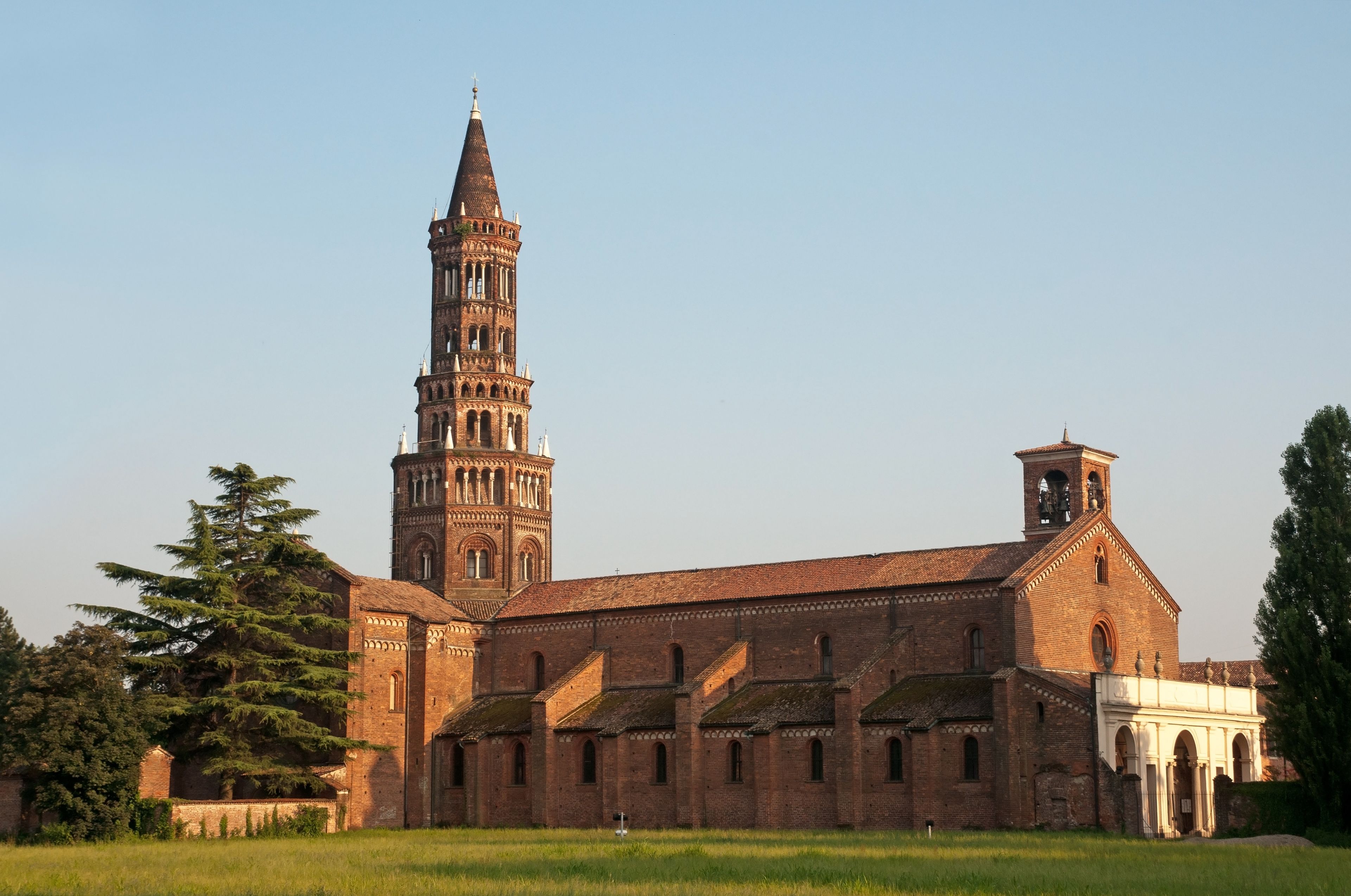 A historic church with a tall bell tower and a large field in the foreground.